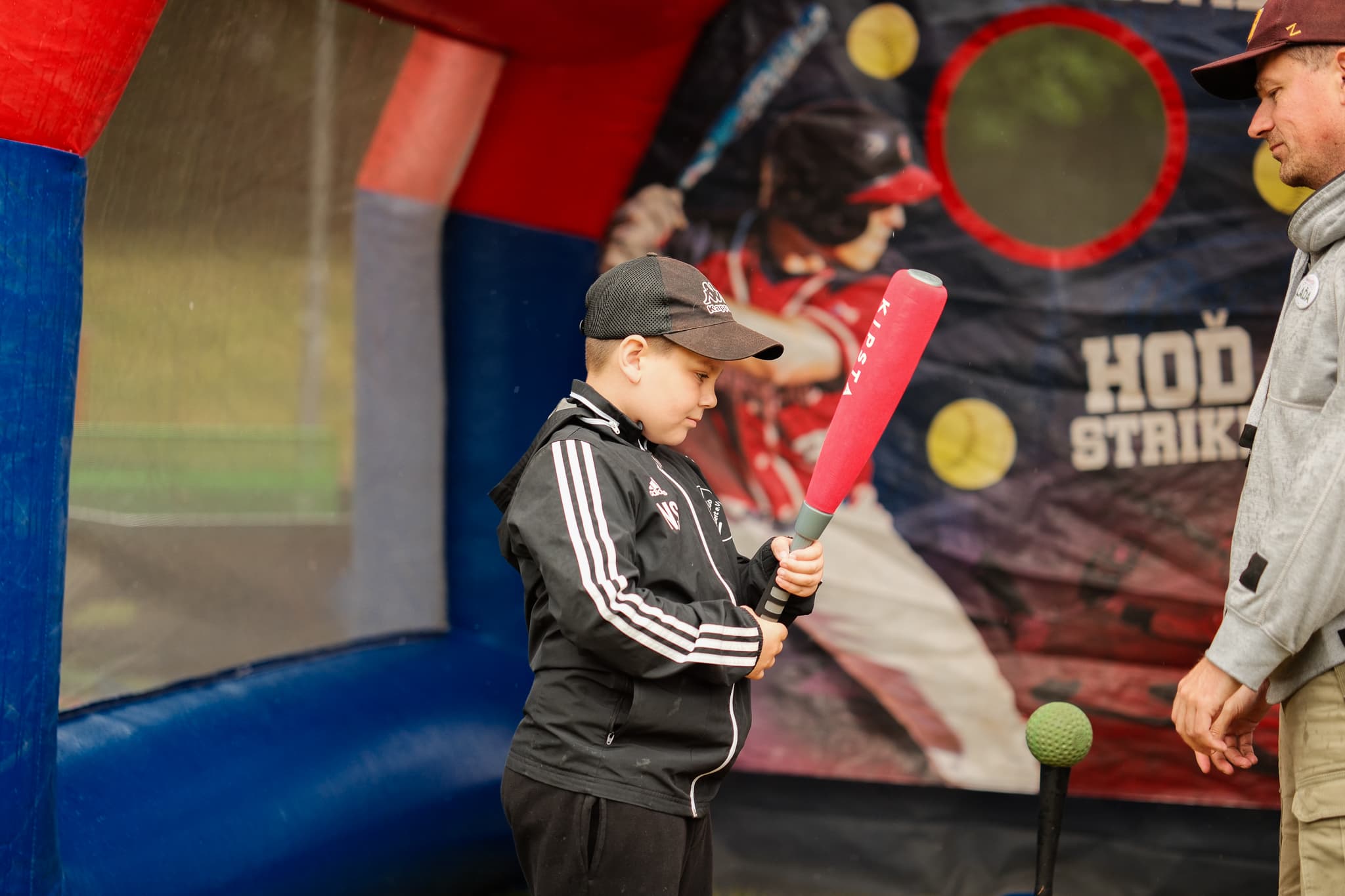 Chlapec v kšiltovce se chystá odpálit míček v softbalové soutěži