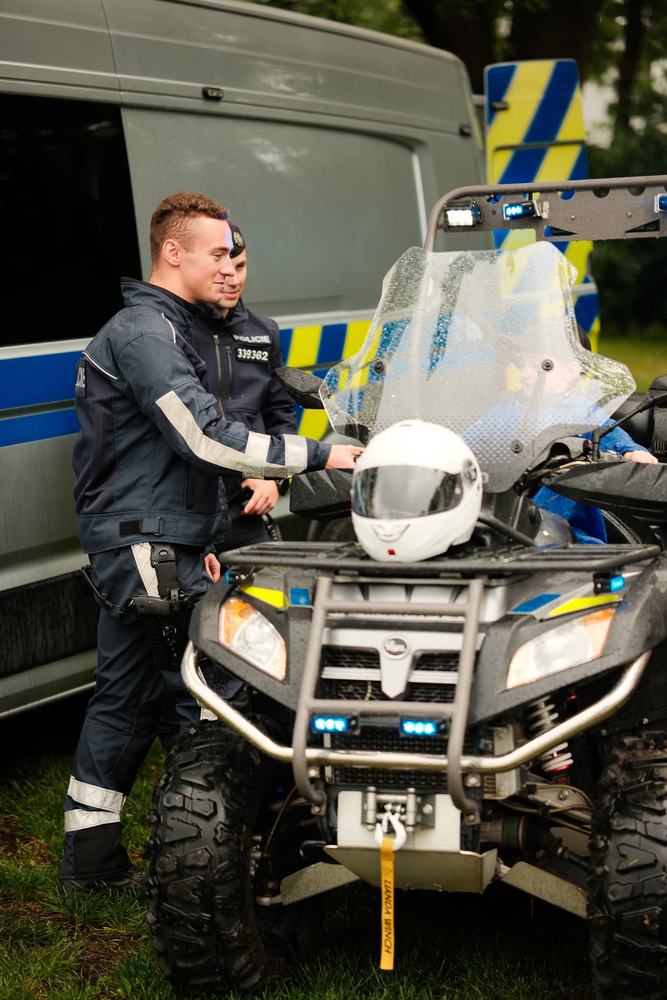 Policista ukazuje dítěti zásahovou čtyřkolku s přilbou během Dne dětí