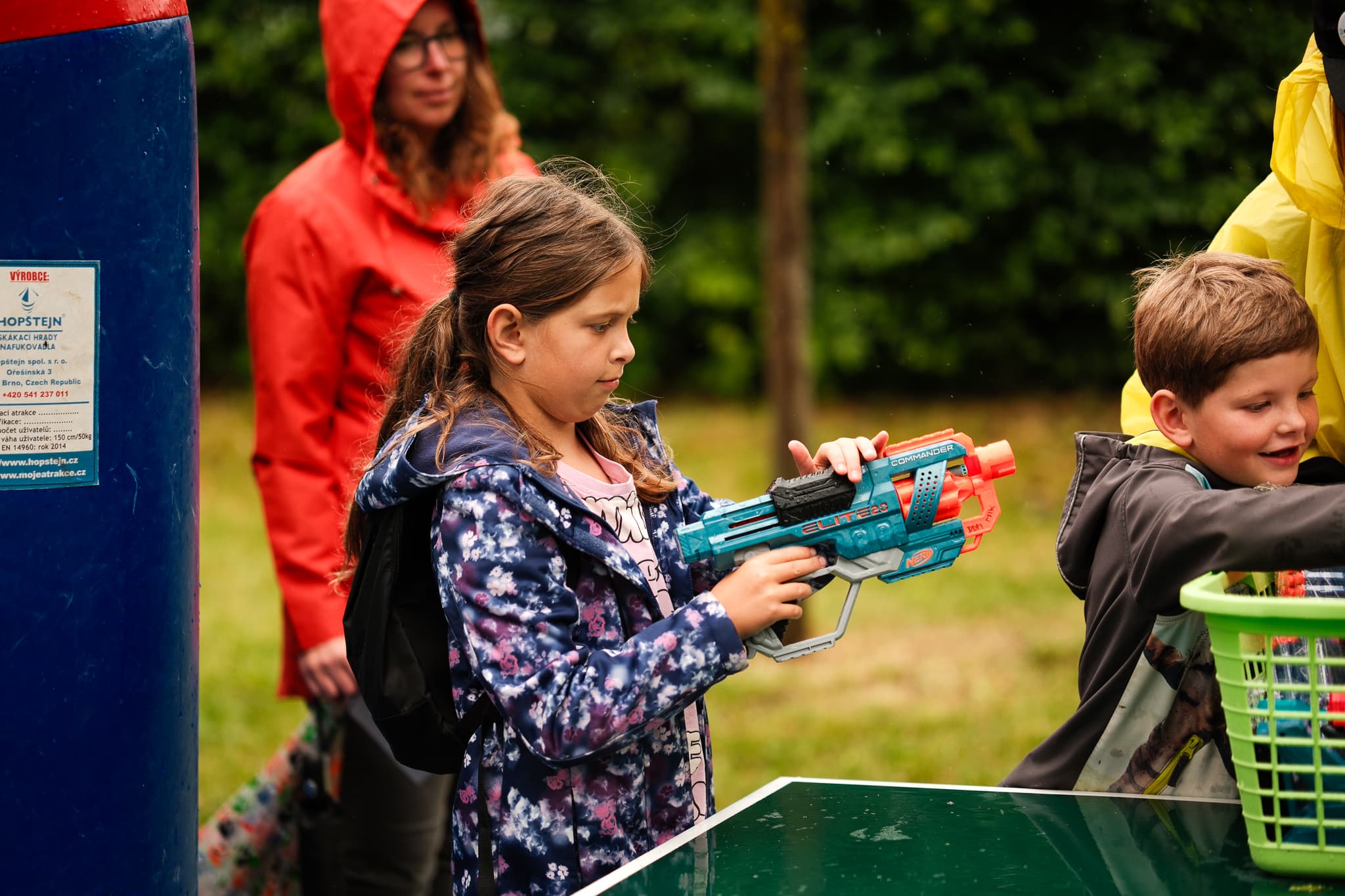 Dívka v dešti střílí pěnovou pistolí na cíl během dětské soutěže