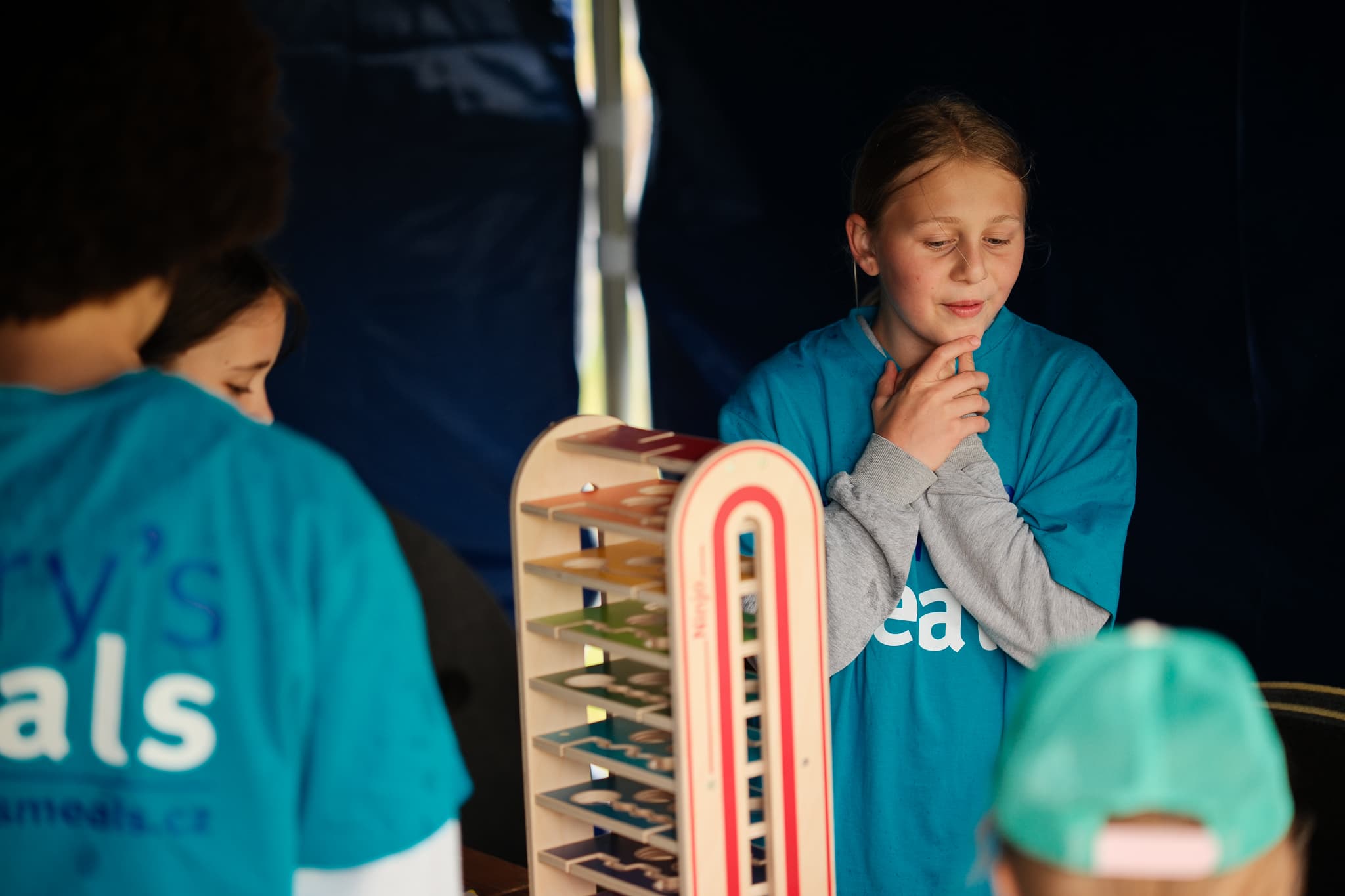 Děti v tričkách Mary's Meals u dřevěné motorické hry ve stanu