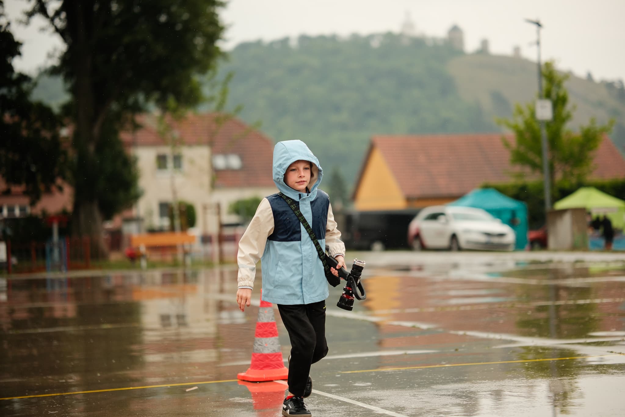 Chlapec s proudnicí běží mokrým náměstím, v pozadí zámecký vrch v Mikulově